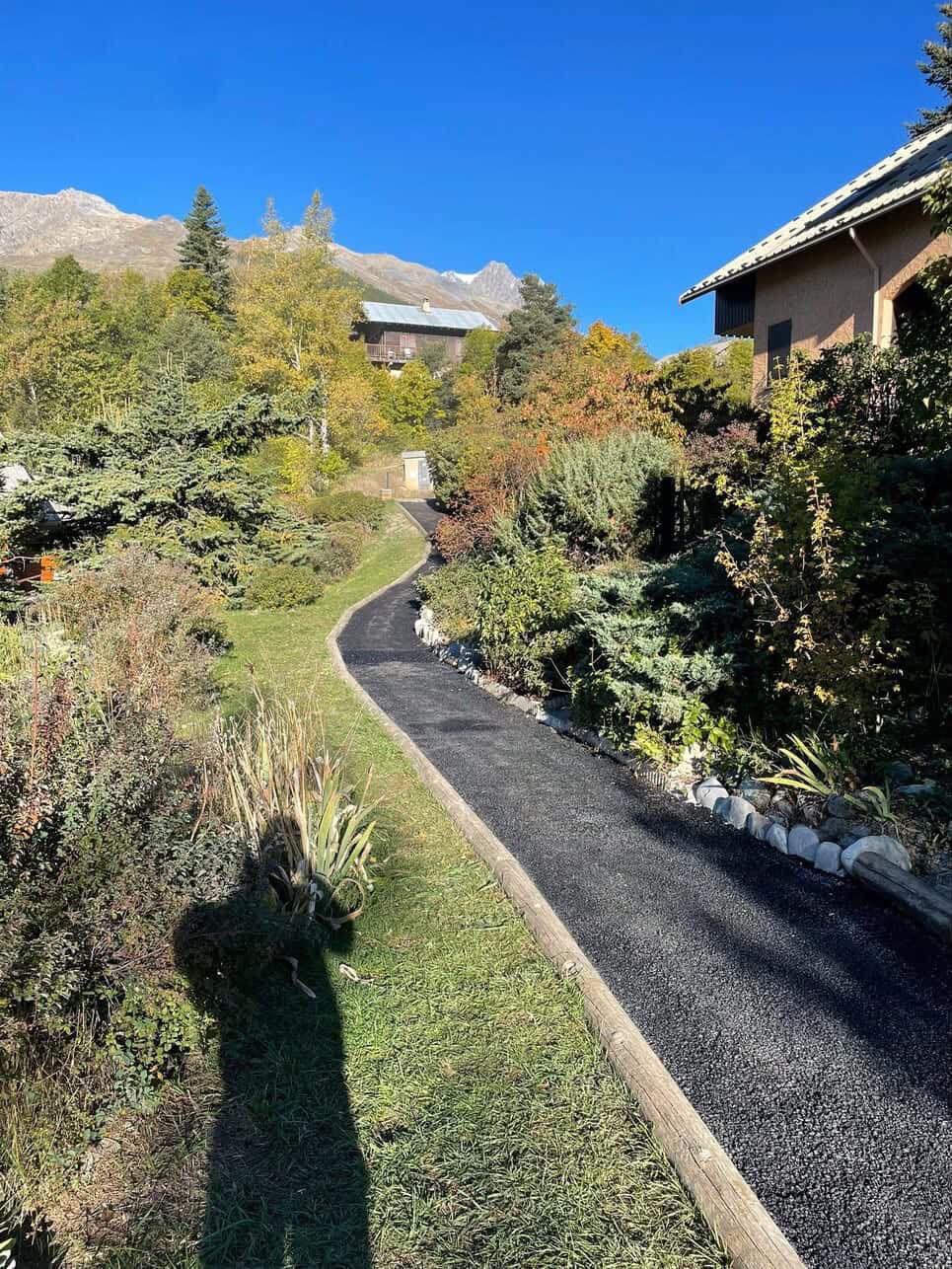 Allée goudronnée sinueuse à travers un jardin paysagé