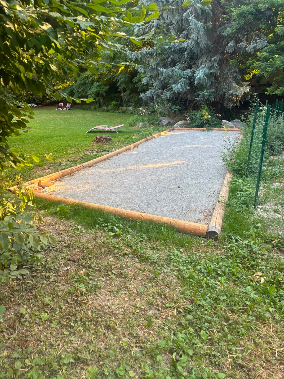 Terrain de pétanque terminé, bordé de rondins de bois